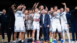 Fourth-year guard Sebastian Thomas (middle) poses with the Hall of Fame Classic MVP trophy after leading URI to a 85-79 victory over Temple University on Saturday