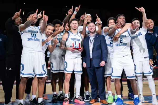 Fourth-year guard Sebastian Thomas (middle) poses with the Hall of Fame Classic MVP trophy after leading URI to a 85-79 victory over Temple University on Saturday