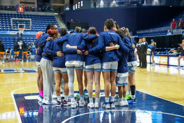 Women’s basketball huddles up before the start of a game. PHOTO CREDIT: Emma Roberts | Staff Photographer